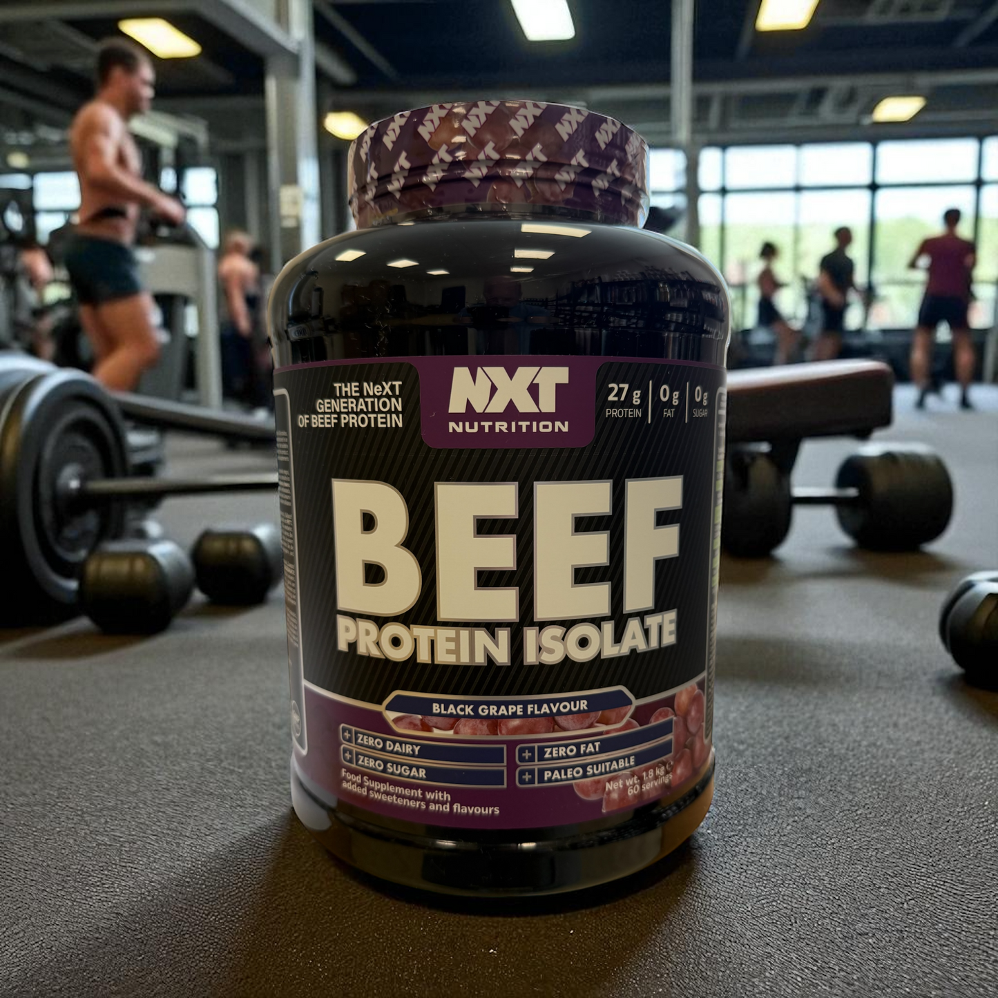 NXT Nutrition Beef Protein Isolate black grape container in a gym setting