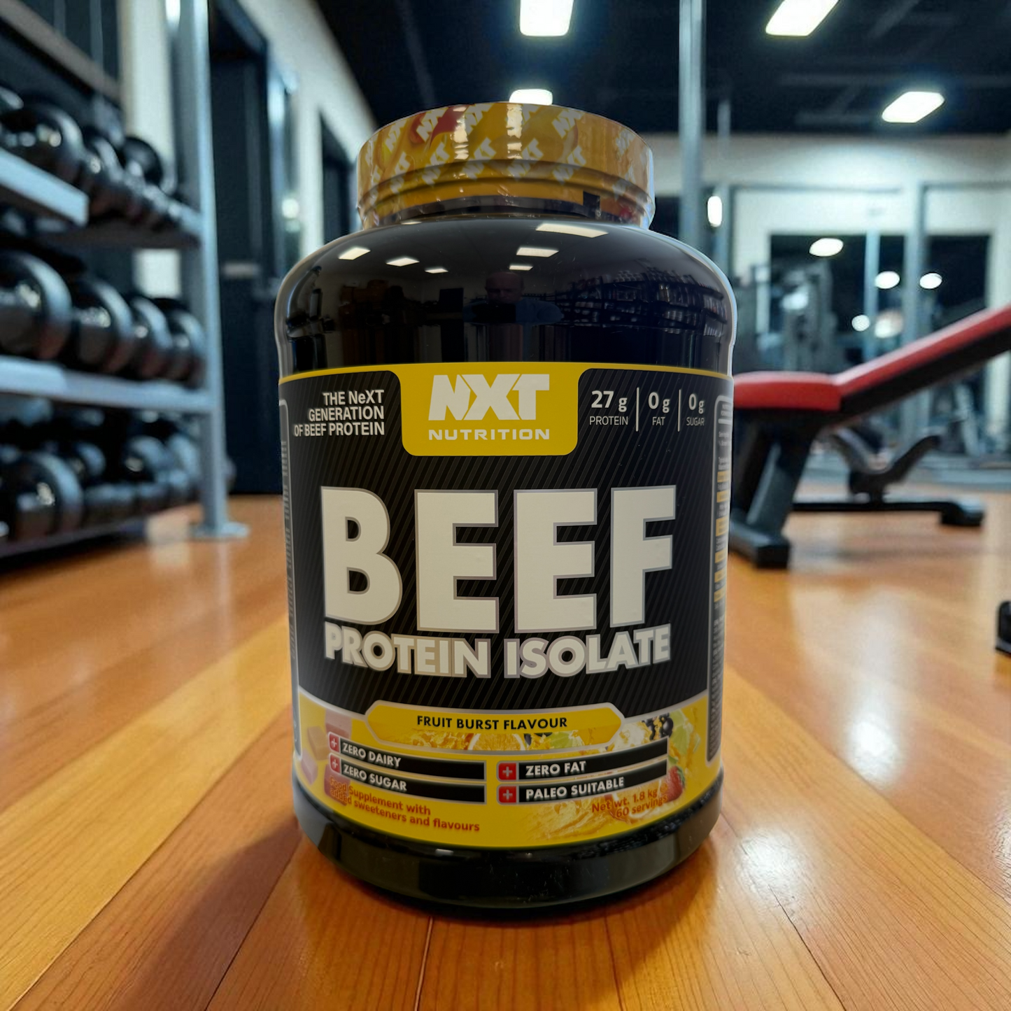 Beef protein isolate container on a gym floor with gym equipment in the background