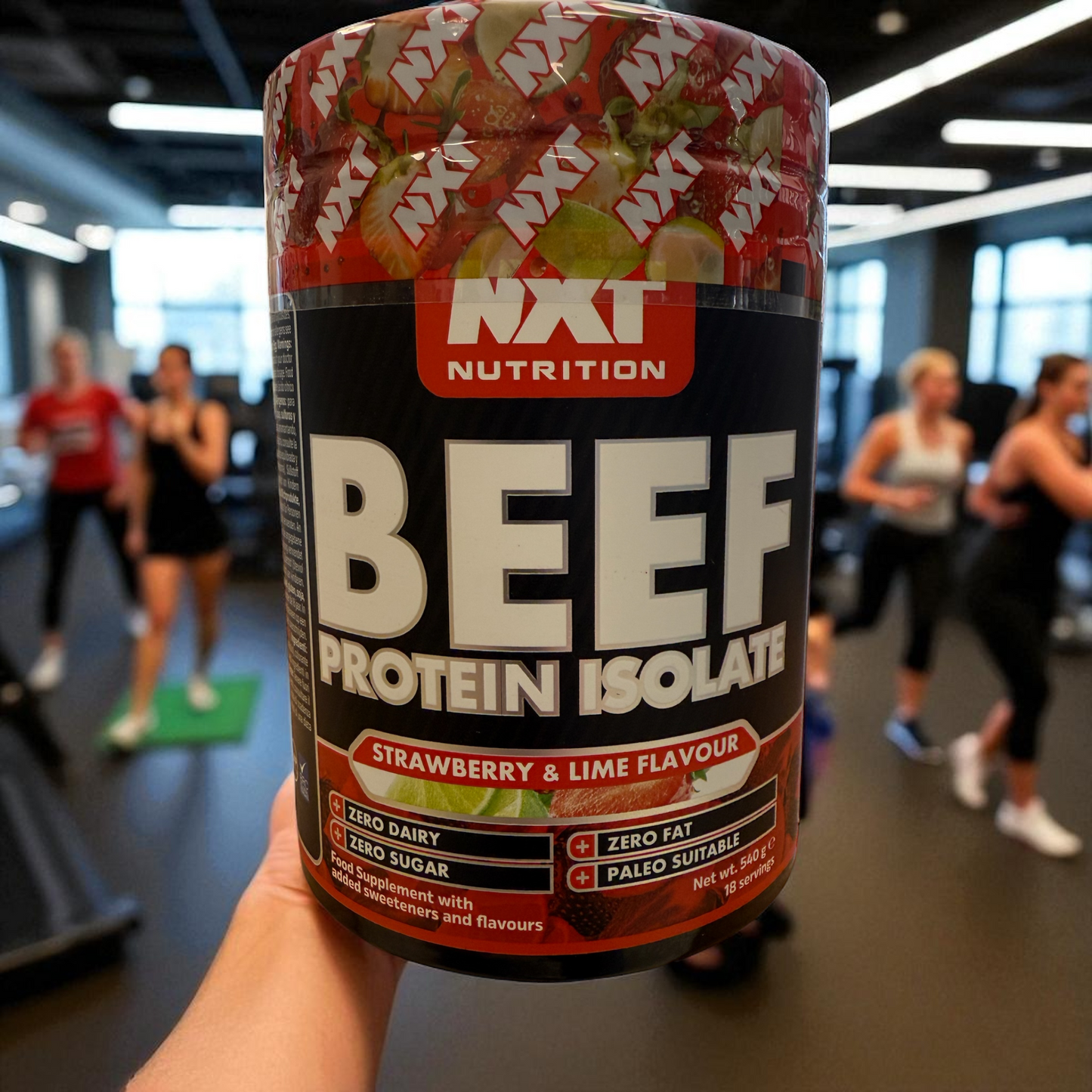 NXT Nutrition Beef Protein Isolate container with strawberry & lime flavor in a gym setting