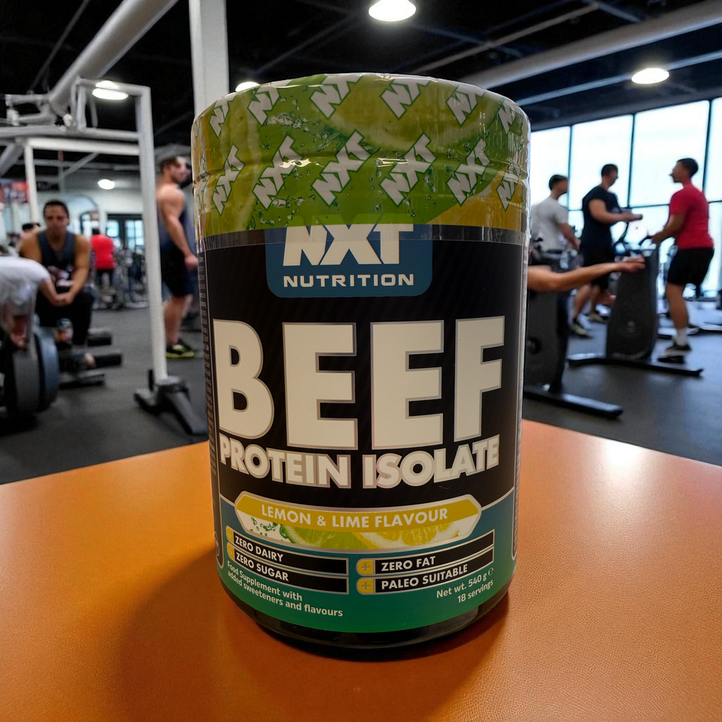 NXT Nutrition Beef Protein Isolate container on a table in a gym setting in lemon and lime flavour