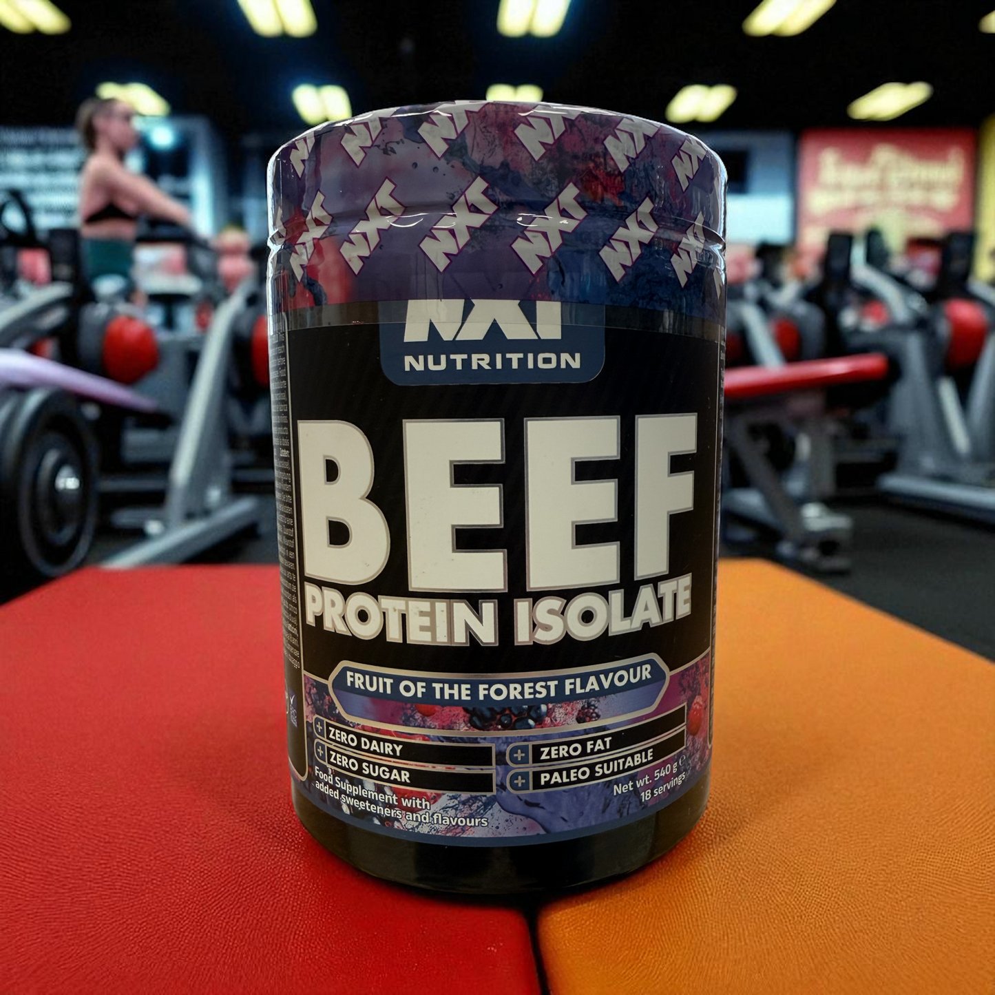 Beef protein isolate container with 'NXN Nutrition' branding in a gym setting in ruit of the forest