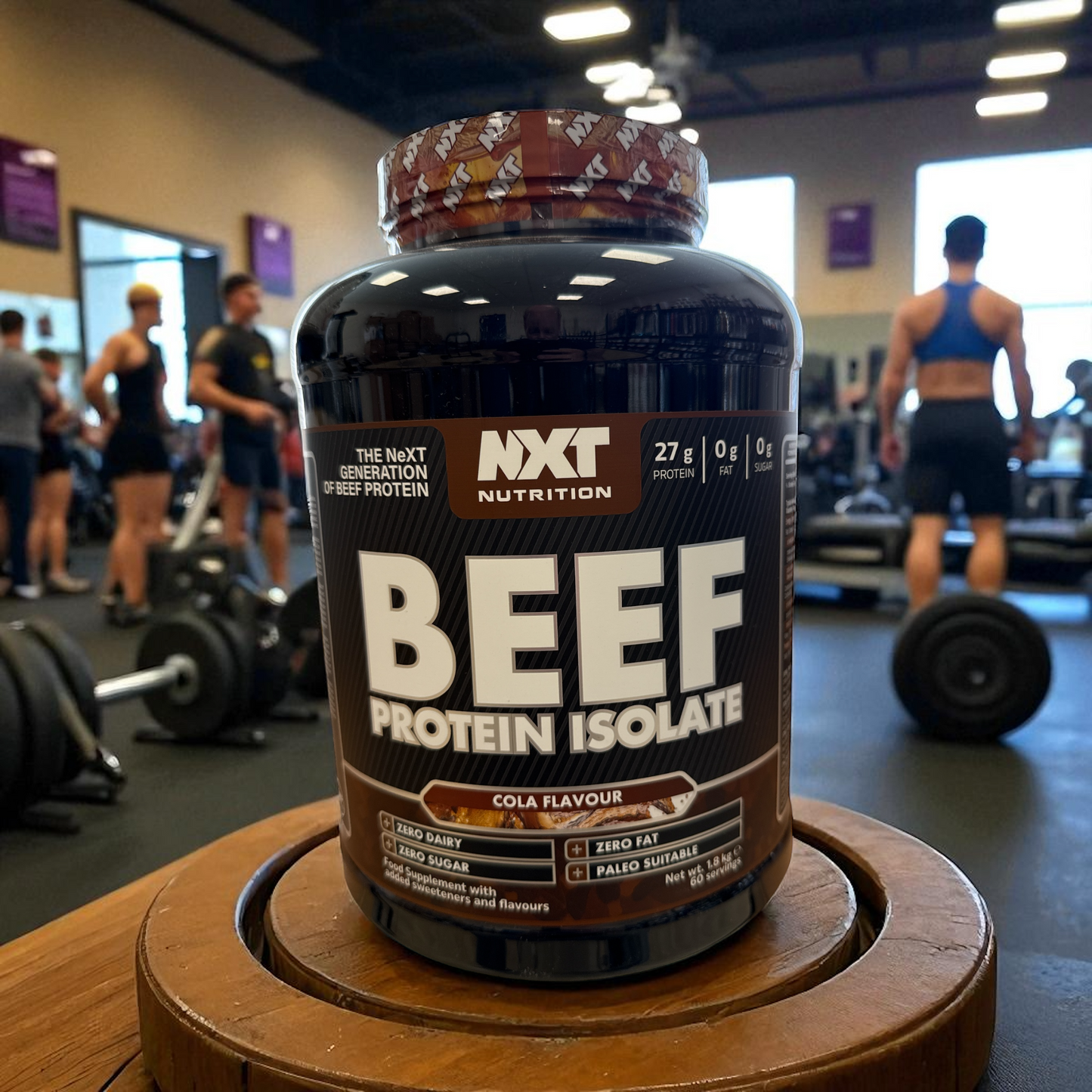 NXT Nutrition Beef Protein Isolate container in a gym setting in cola flav