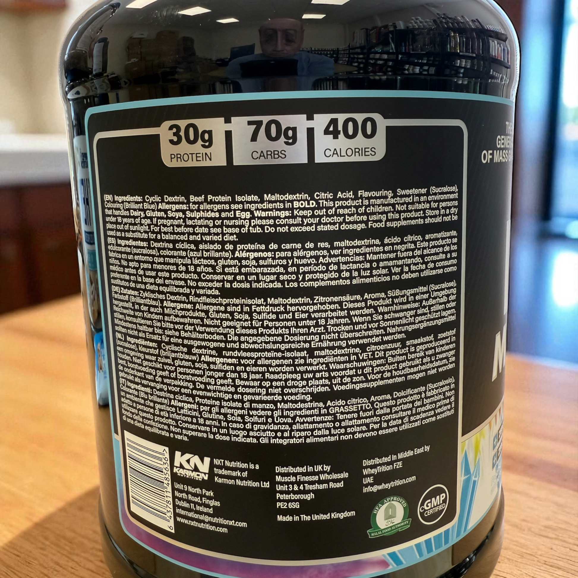 Back label of a supplement container with nutritional information and branding on a wooden surface.
